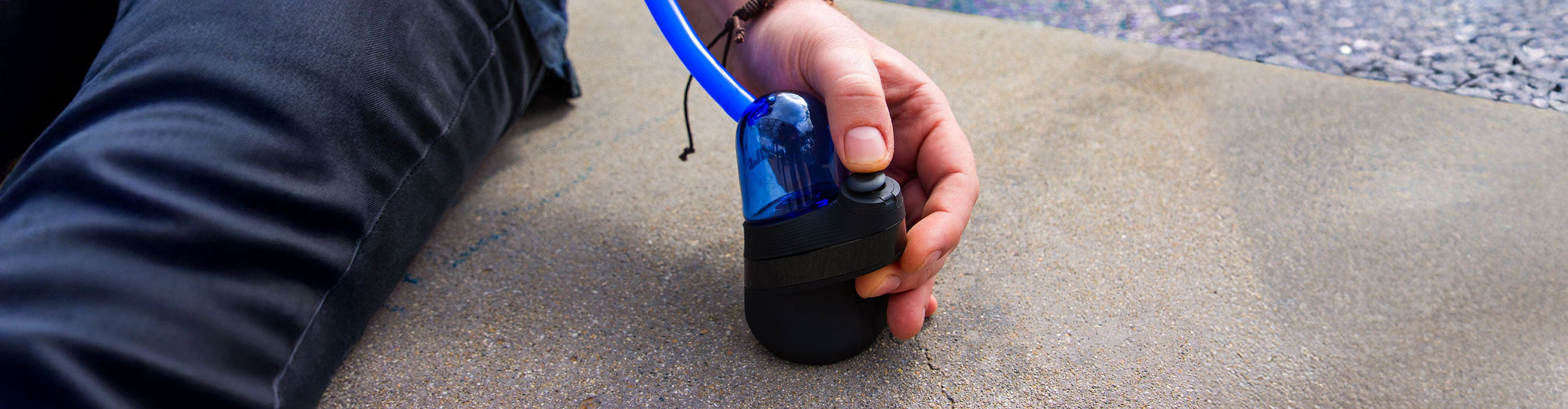 man using the Puffco Peak with Wulf Link Glass Attachment at park with water fountain in background