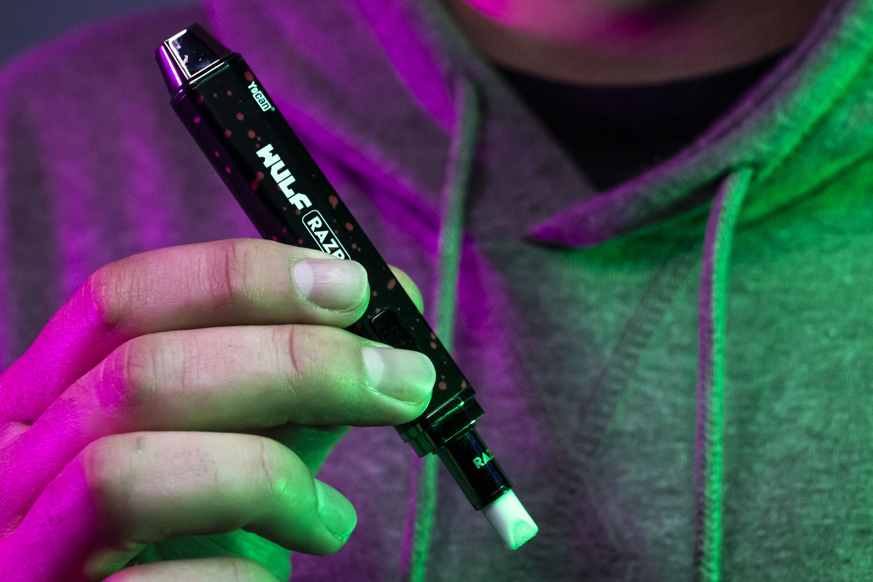 Man holding Wulf RAZR underneath purple and green studio background