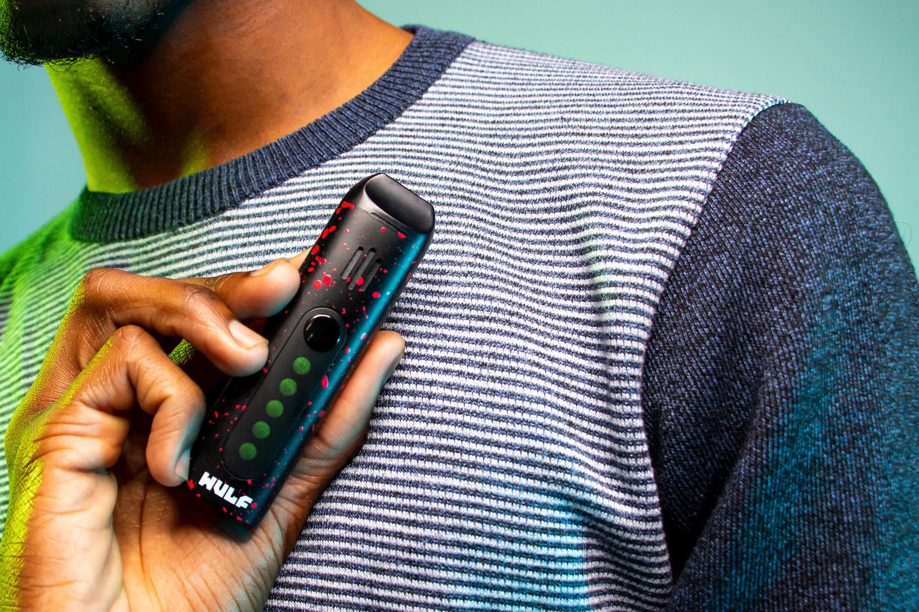Man holding Wulf Flora Vaporizer in front of teal and blue studio background